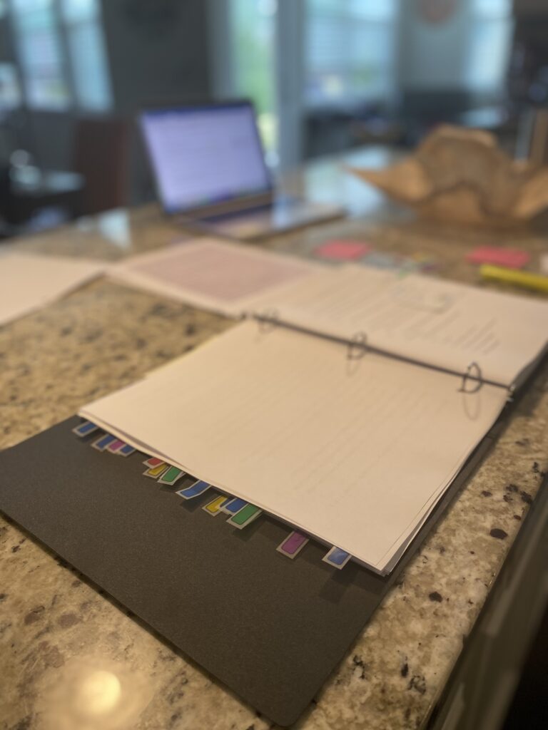 An open manuscript binder filled with colorful tabs, marked up during a developmental editing project at cocostudio.